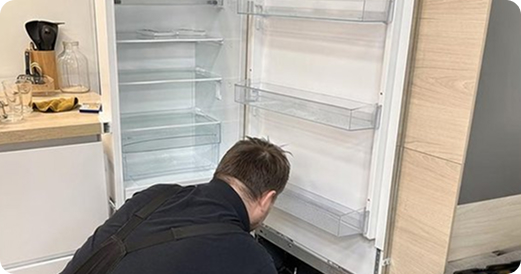 Мастер сервисного центра Candy ремонтирует встроенный холодильник в Мытищах